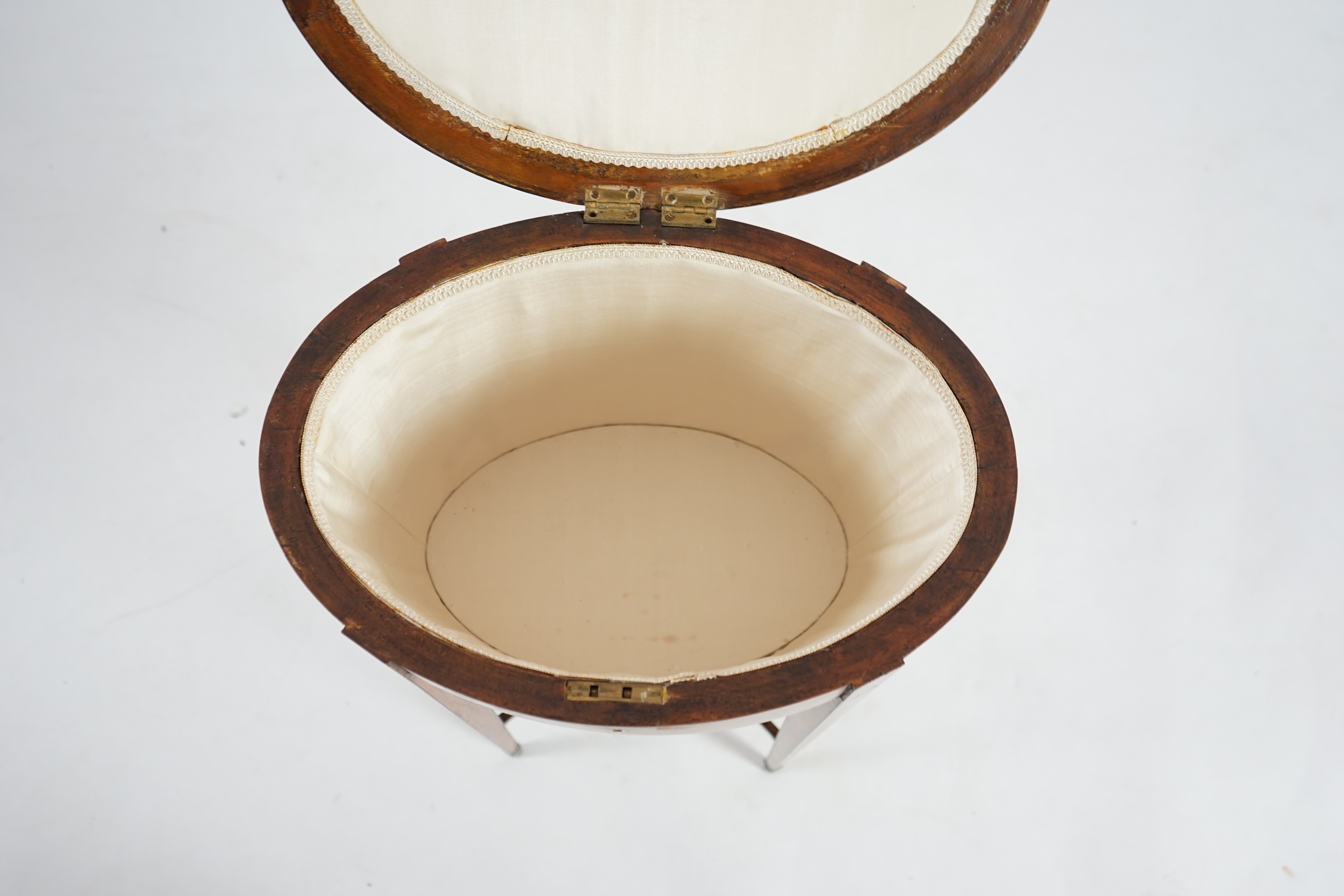 An Edwardian Sheraton revival satinwood work table, with oval top, on squared tapered legs, 44cm wide, 31cm deep, 72cm high. Condition - a little faded with a repaired split and some staining across the lid, some adaptat